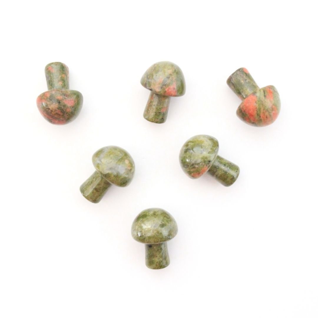A photo of small crystal mushrooms made from unakite, a type of metamorphic rock that typically consists of green epidote and pink orthoclase feldspar. Each mushroom has a rounded cap and a short stem, and has been polished to a smooth and shiny finish