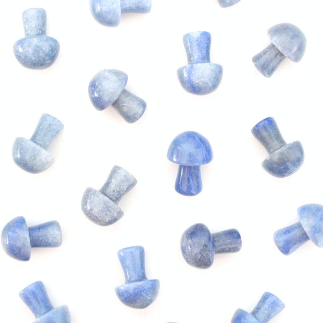 A photo of small crystal mushrooms made from blue aventurine, a type of quartz mineral that is known for its shimmering appearance and blue colour. Each mushroom has a rounded cap and a short stem, and has been polished to a smooth and shiny finish. 